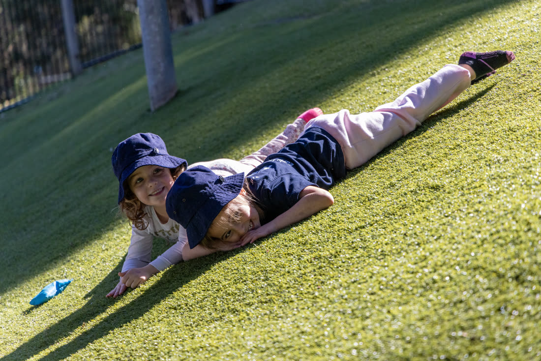 A child rolling down the grassy hill