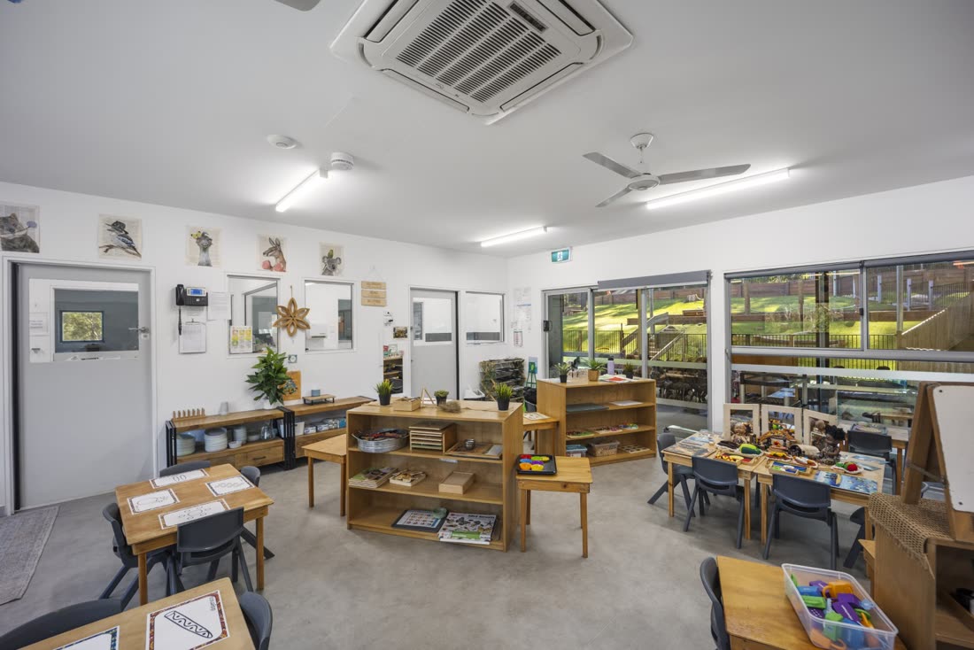 A bright classroom with Montessori shelves and child-sized tables