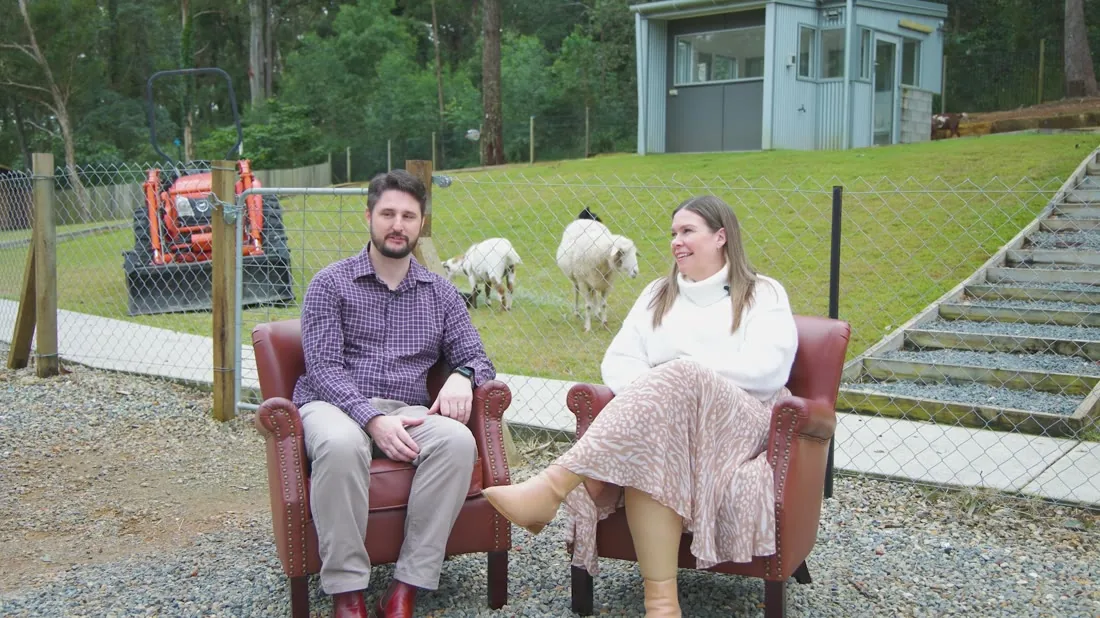 Two parents sharing their experience, with the sheep and goats behind them